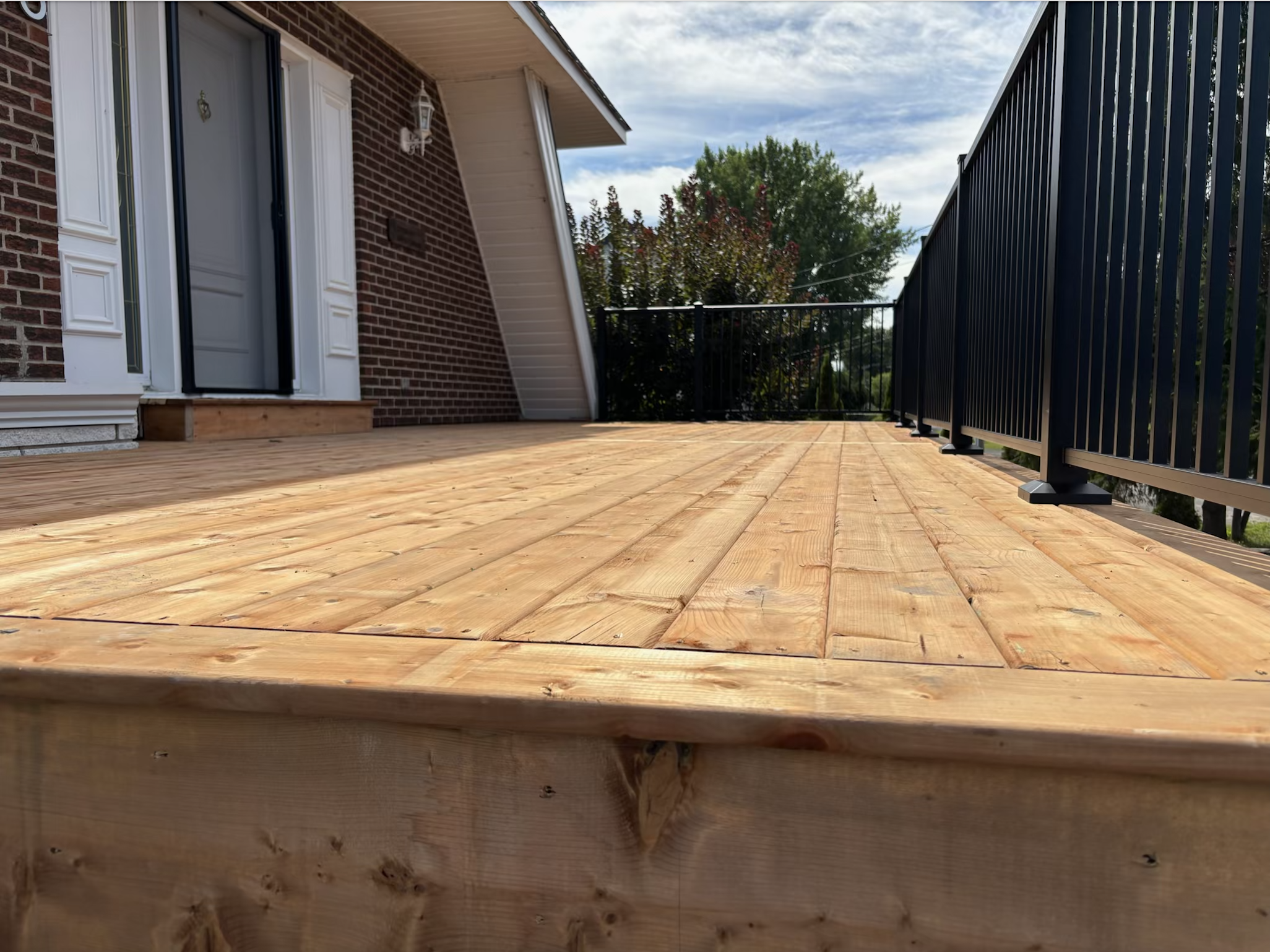 Vue d'un patio en bois traité avec rampe en métal noir mat.